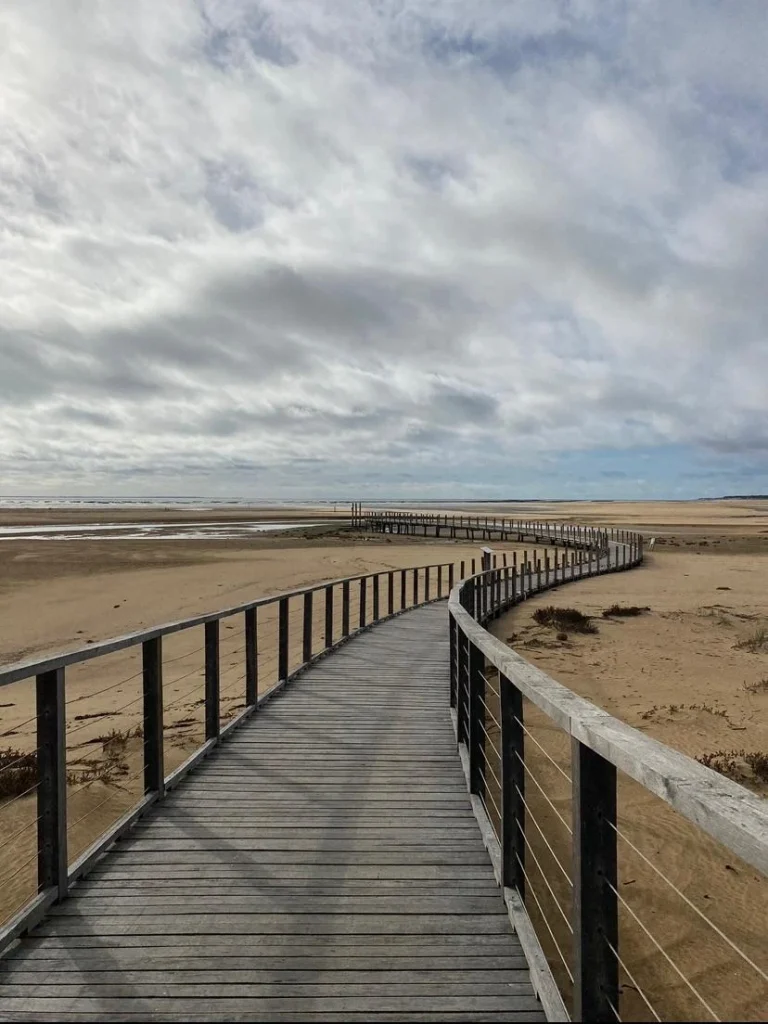 image de la plage avec en son centre un chemin sur ciel nuageux